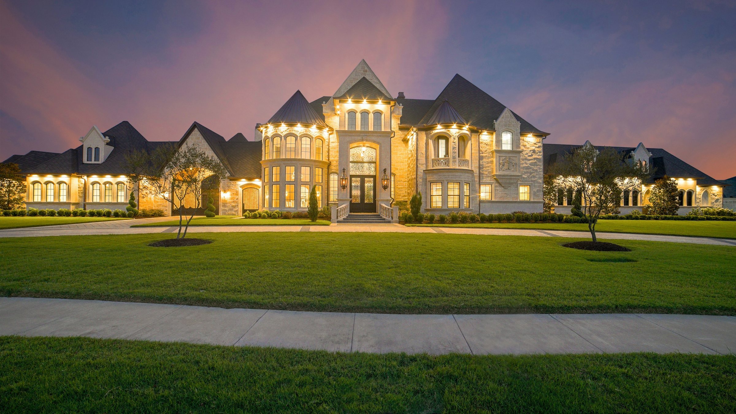 A stone estate home lit up at twilight